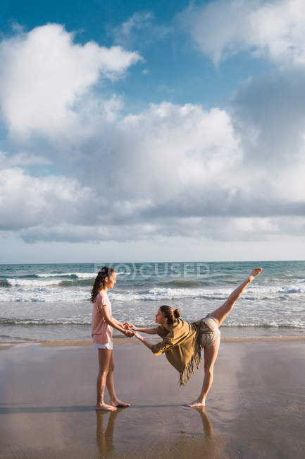 Freundinnen machen Übungen am Strand bei bewölktem Himmel — Stockfoto
