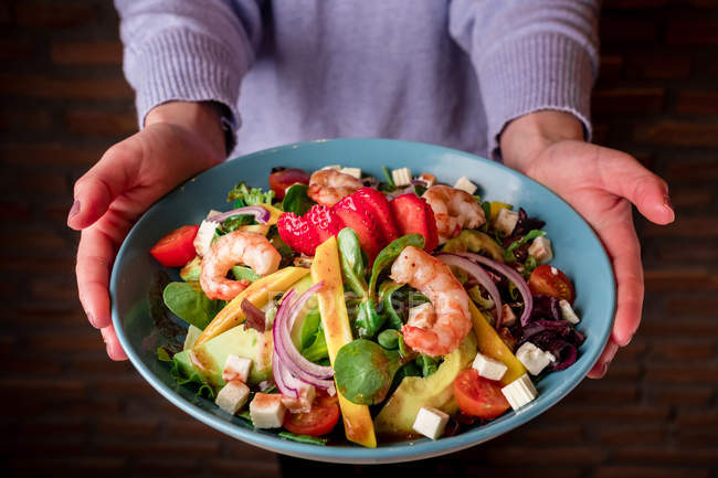Mains humaines tenant bol de salade de légumes aux crevettes — Photo de stock