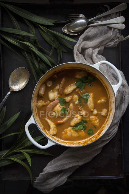 Sopa de peixe cozida saborosa com batatas em panela servida na superfície preta — Fotografia de Stock
