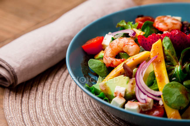 Close-up of Vegetable salad with shrimps in blue bowl on mat — Stock Photo
