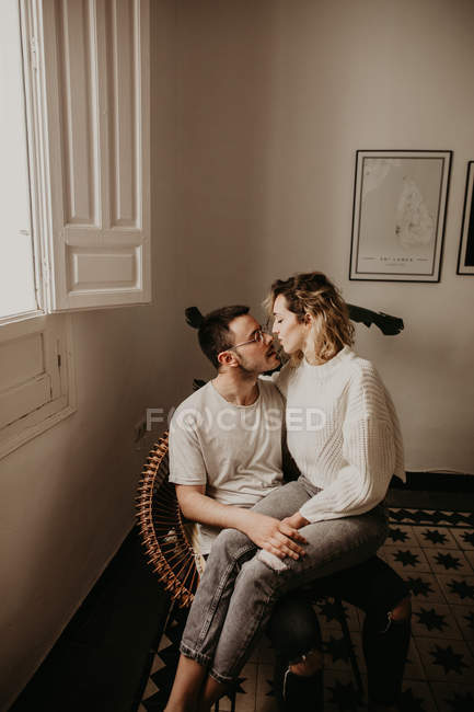 Счастливая пара сидит в кресле и смотрит друг на друга, сближаясь дома — стоковое фото