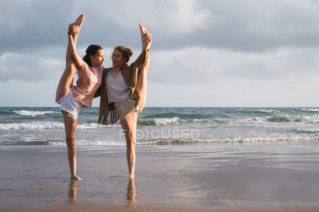 Amiche che fanno esercizi sulla spiaggia sotto il cielo nuvoloso — Foto stock