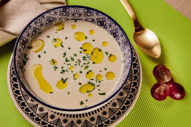 Крупный план сливочного супа с маслом в чаше с узором на зеленой салфетке — стоковое фото