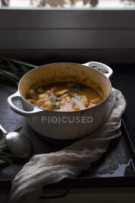 Вкусный вареный рыбный суп с картошкой в горшочке подается на черной поверхности — стоковое фото