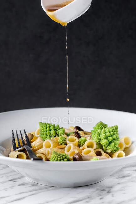Sauce pouring to appetizing pasta with romanesco cauliflower. — Stock Photo