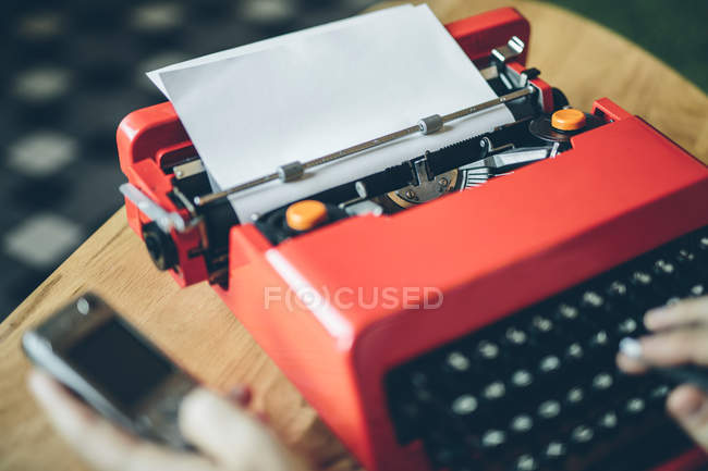 Close-up máquina de escrever vermelha em mesa pequena com folha de papel inserida — Fotografia de Stock