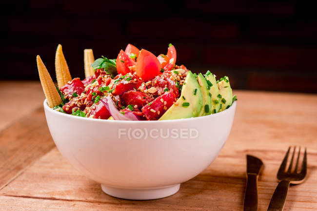 Чаша вкусного овощного салата с авокадо на деревянном столе — стоковое фото