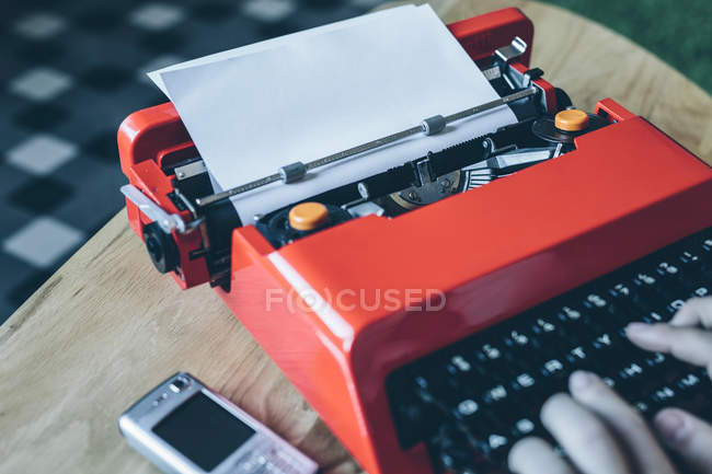 Person typing on red typewriter on table — Stock Photo