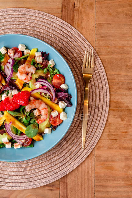 Primo piano d'insalata di verdure con gamberetti in boccia azzurra su tappetino — Foto stock