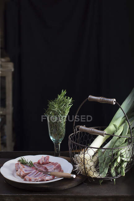 Raw meat and green herbs prepared for cooking on a table. — Stock Photo