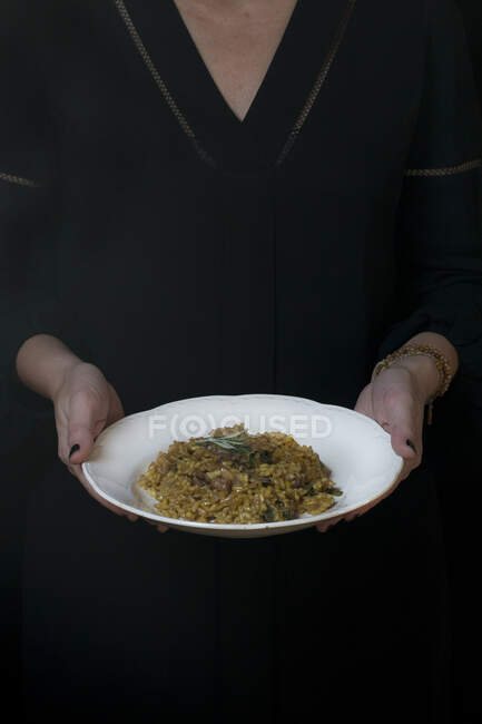 Mãos de cozinheiro irreconhecível segurando prato com risoto. — Fotografia de Stock