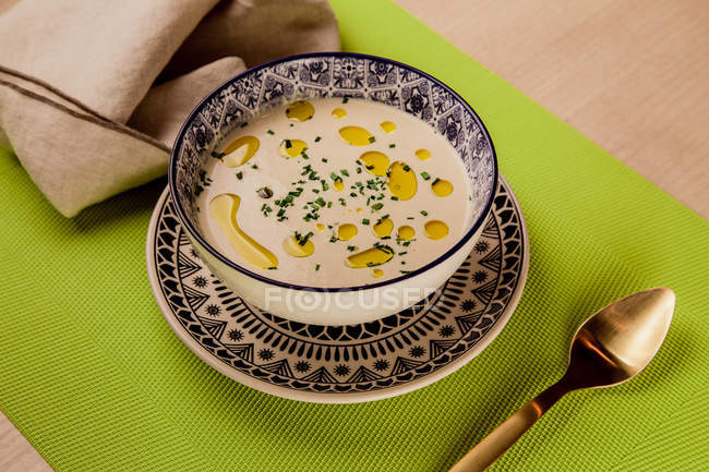 Cream soup with oil in patterned bowl on green napkin — Stock Photo