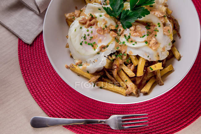 Porção apetitosa de ovos escalfados servidos em prato com batatas fritas — Fotografia de Stock