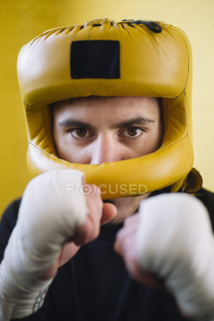 Confident fighter man with bandaged arms in helmet looking at camera. — Stock Photo