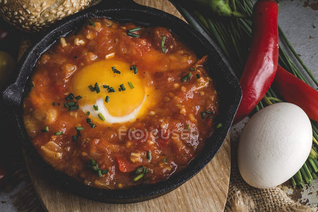 Fried egg with tomato and red and green peppers in frying pan — Stock Photo