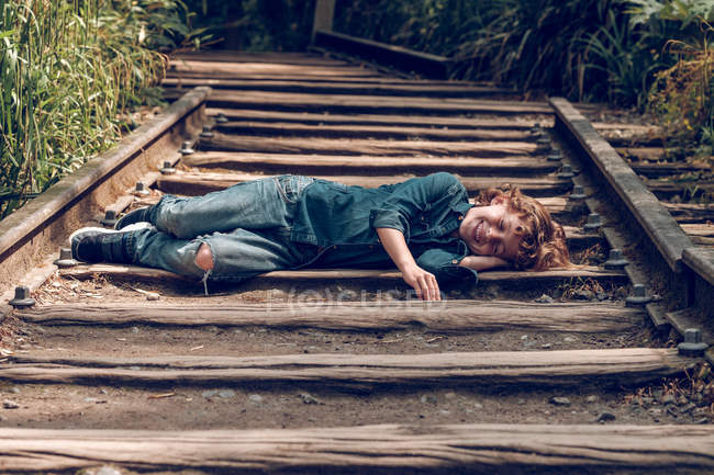 Dirty boy sleeping on railroad — Stock Photo