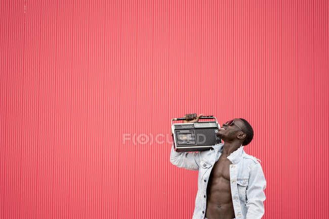 African american man with vintage radio device on red background — Stock Photo