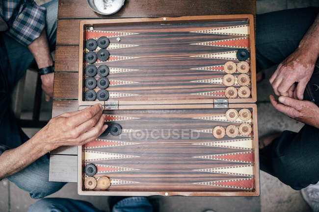 From above shot of two adult men playing backgammon while sitting on street of Istanbul — Stock Photo