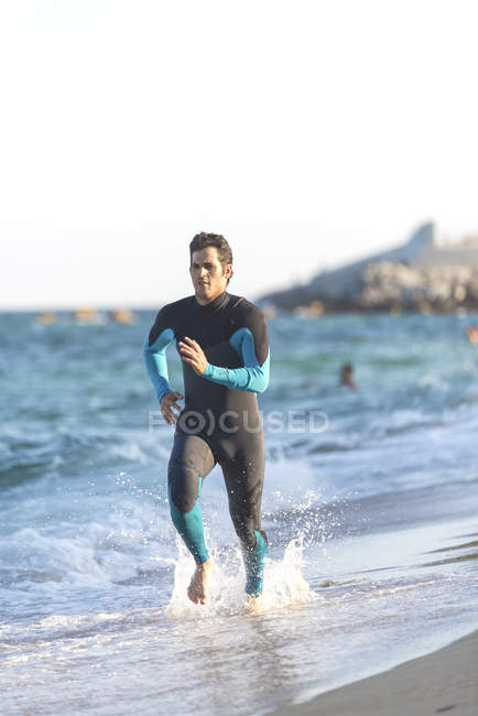 Surfista in neoprene in esecuzione sulla spiaggia — Foto stock