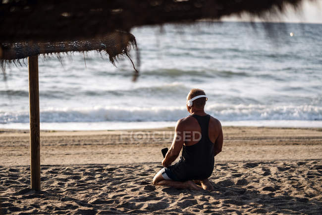 Anciano escucha música en la playa - foto de stock
