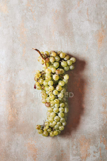 Ramo de uvas verdes en la superficie de madera en mal estado - foto de stock