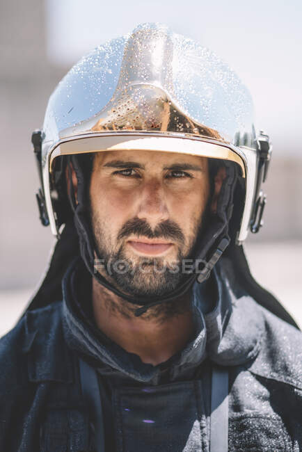 Пожарный позирует со шлемом, смотрит в камеру.. — стоковое фото