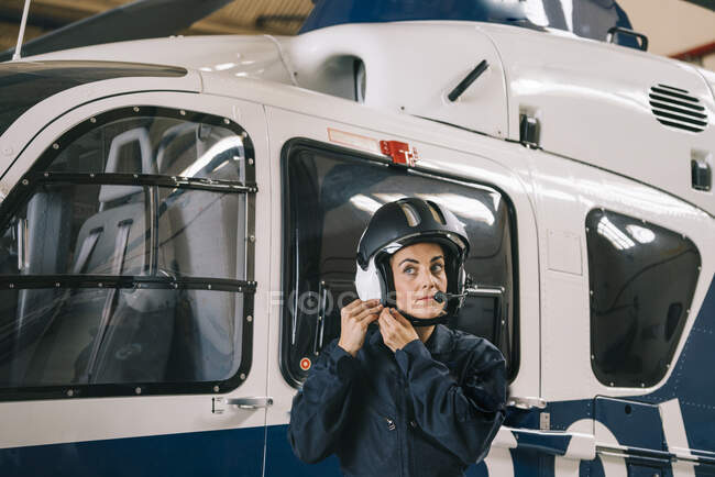 Девушка-пилот позирует с вертолетом и шлемом — стоковое фото