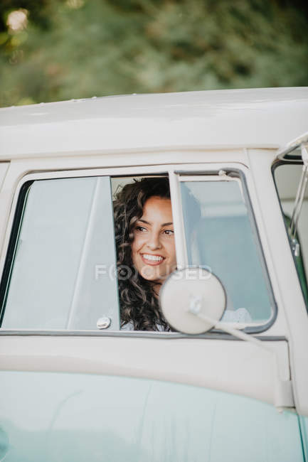 Jovem morena mulher olhando embora enquanto sentado dentro do carro vintage no fundo borrado da natureza — Fotografia de Stock