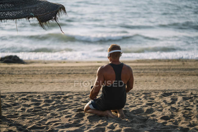 Un homme âgé écoute de la musique sur la plage — Photo de stock