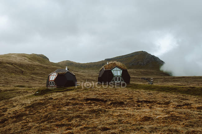 Piccole case contemporanee sul campo con erba secca sulle colline sulle isole Feroe — Foto stock