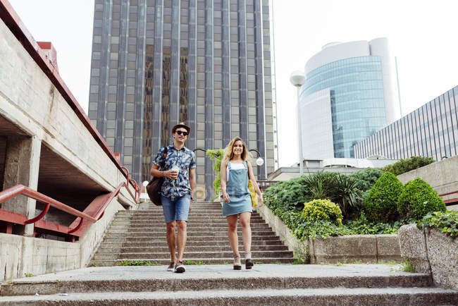 Stylish casual man and woman walking downstairs on street in thee city — Stock Photo