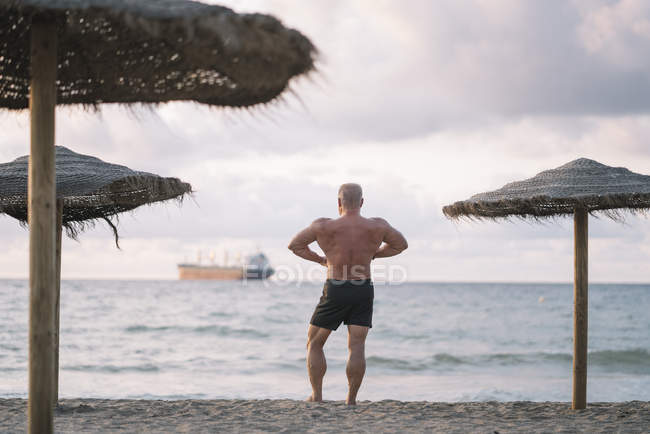 Strong old man makes exercise on the beach — Stock Photo