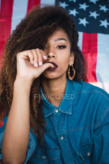 Mujer joven sentada contra la bandera de América - foto de stock