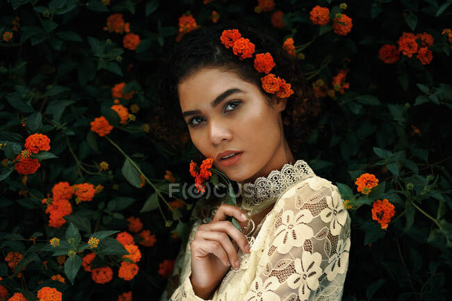 Atractiva joven mujer en blusa y falda cerca de arbusto de flores - foto de stock