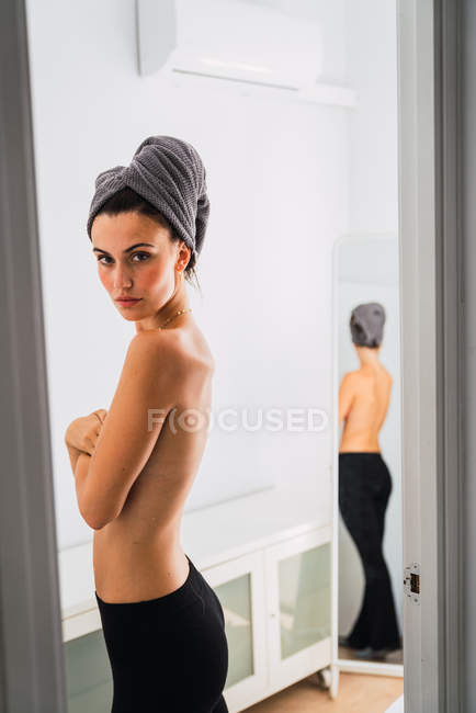 Junge Oben-Ohne-Frau mit Handtuch auf dem Kopf vor Spiegel — Stockfoto