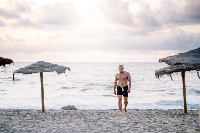 Строгий старик, идущий по пляжу — стоковое фото