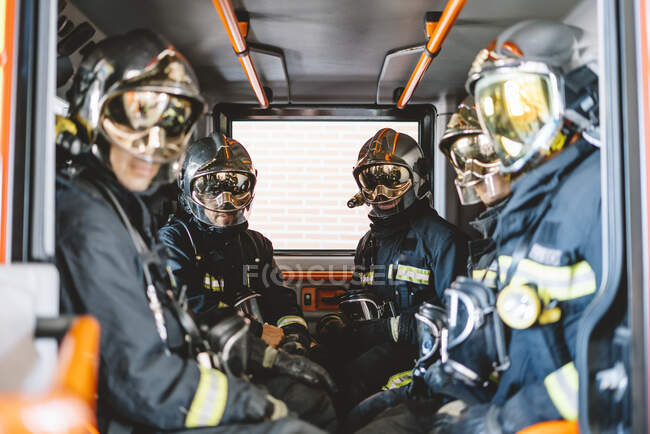 Bombeiros irreconhecíveis com capacete em um veículo de emergência — Fotografia de Stock