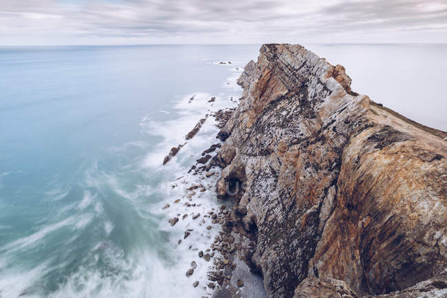 Дивовижний вид на морську воду, що бризкала біля стрімких скель у похмурий день в Астурії (Іспанія). — стокове фото