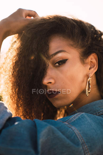 African American woman in makeup looking aside in sunlight — Stock Photo