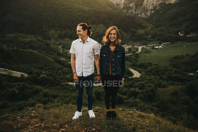 Mann und Frau schauen weg, während sie auf dem Hintergrund von erstaunlichen Bergen und Tälern zusammen stehen — Stockfoto