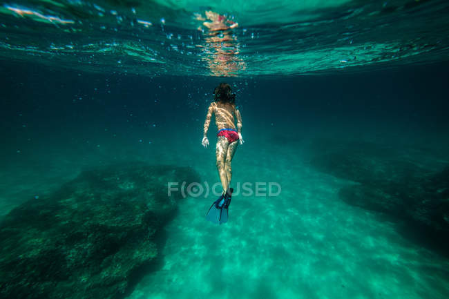 Anonymous boy snorkeling in sea water — Stock Photo