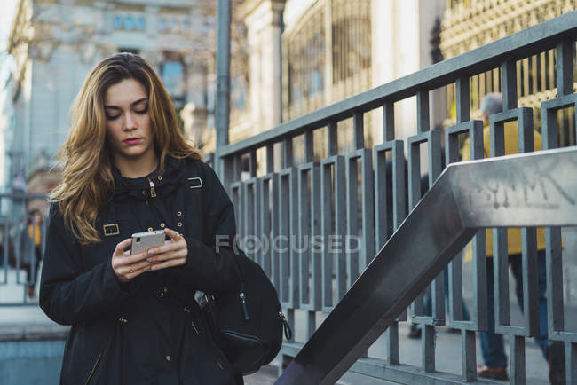 Жінка використовує смартфон біля метро в місті — стокове фото