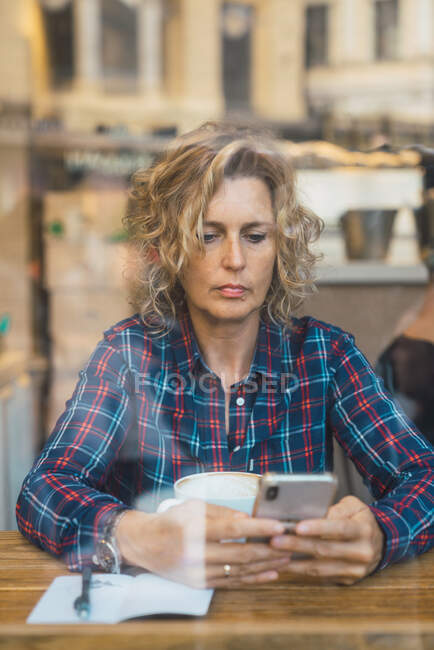 Mujer sentada en la cafetería con una taza de café - foto de stock