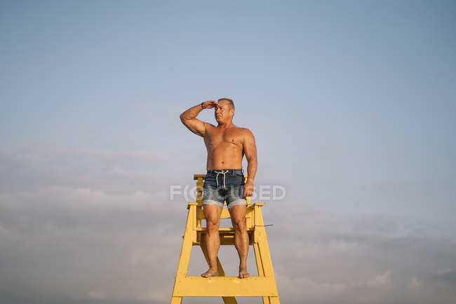 Fuerte rescatador hombre mantiene el reloj en la playa - foto de stock