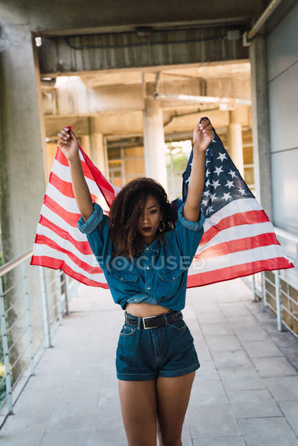 Young African American woman standing on street with flag of USA and looking at camera — Stock Photo