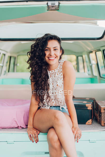 Весела брюнетка сидить у яскравому фургоні — стокове фото