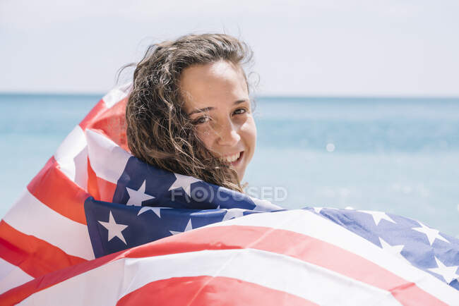 Une fille posant sur la plage avec le drapeau des États-Unis. — Photo de stock