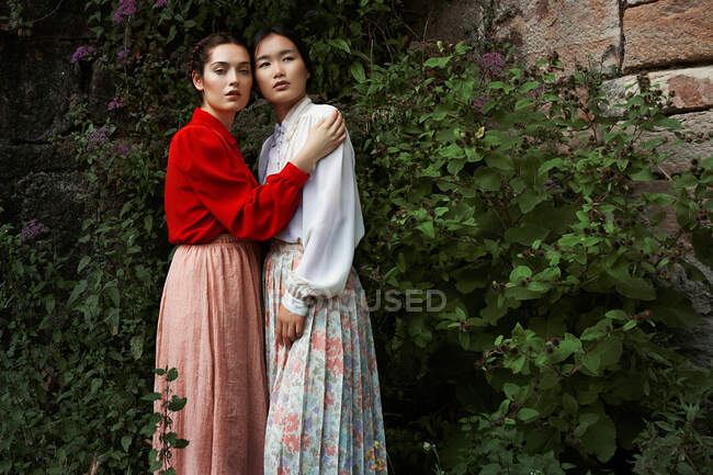 Attraktive multiethnische Damen umarmen den Blick in die Kamera — Stockfoto