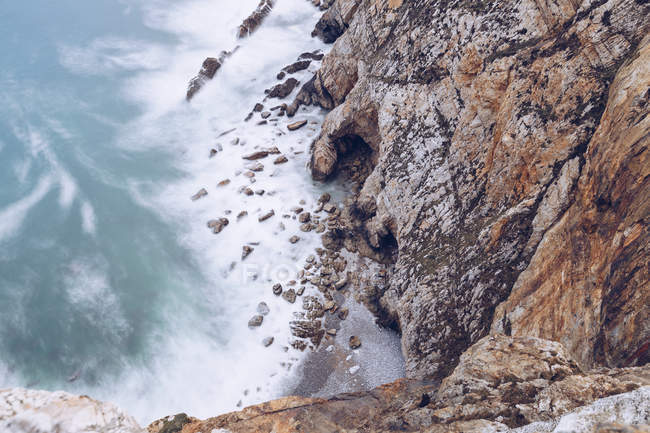 Increíble vista del agua de mar salpicando cerca de un largo acantilado rocoso en un día nublado en Asturias, España - foto de stock