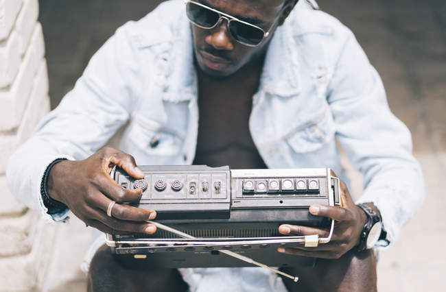 Jeune homme concentré assis avec dispositif de radio vintage — Photo de stock